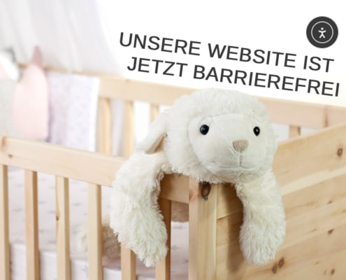 Ein Kuscheltier scheint aus unserem Gitterbett aus Zirbenholz zu klettern. Auf dem Bild steht die Botschaft "Unsere Website ist jetzt barrierefrei".